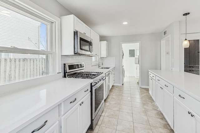 kitchen featuring sink, white cabinetry, decorative light fixtures, appliances with stainless steel finishes, and backsplash