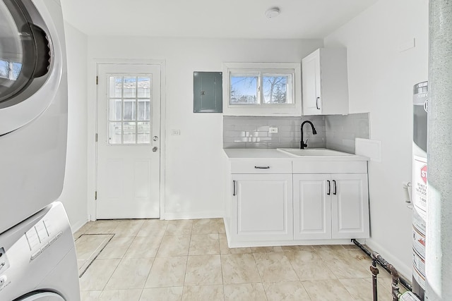 washroom featuring sink, light tile patterned floors, electric panel, cabinets, and stacked washer / drying machine