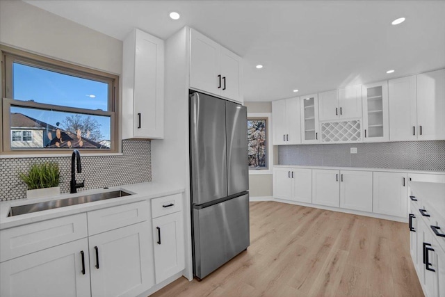 kitchen with sink, light hardwood / wood-style flooring, stainless steel refrigerator, a healthy amount of sunlight, and white cabinets