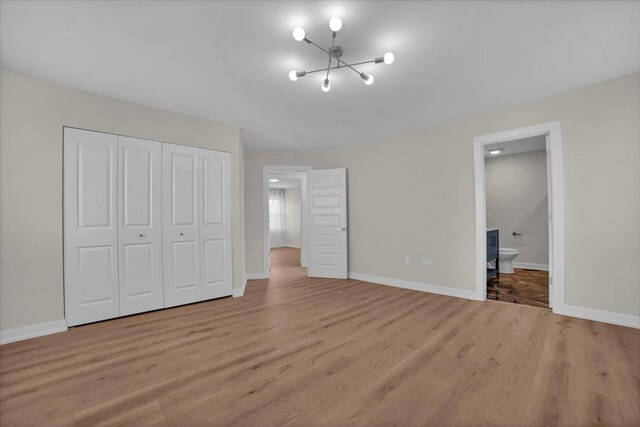 unfurnished bedroom with ensuite bath, light hardwood / wood-style flooring, and a closet