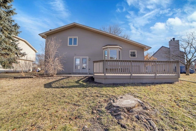 back of property with a deck and a lawn