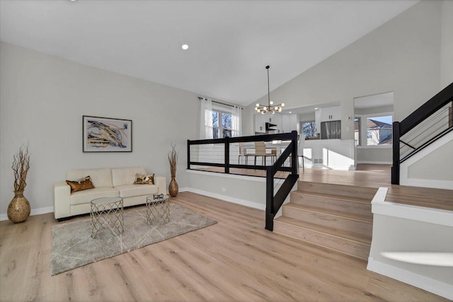 living room with a wealth of natural light, a notable chandelier, and light wood-type flooring