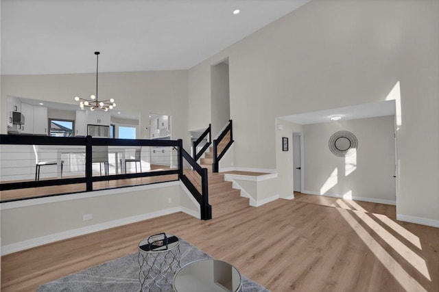 entryway with an inviting chandelier, light hardwood / wood-style flooring, and high vaulted ceiling