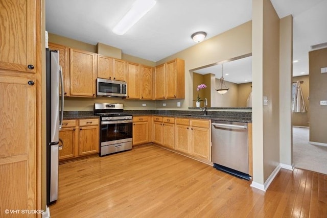 kitchen featuring appliances with stainless steel finishes, light hardwood / wood-style floors, sink, and hanging light fixtures