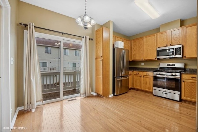 kitchen featuring hanging light fixtures, stainless steel appliances, a chandelier, and light wood-type flooring