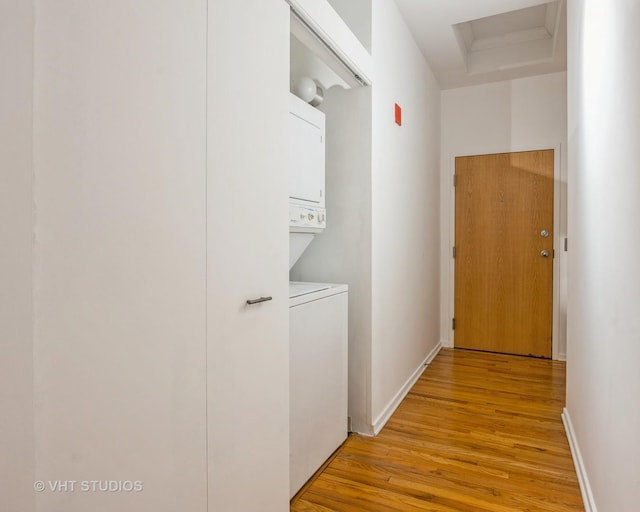 washroom with stacked washer and dryer and light hardwood / wood-style flooring