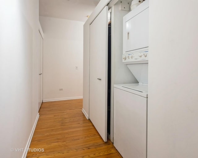 laundry room with light hardwood / wood-style floors and stacked washing maching and dryer