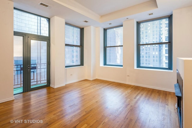 unfurnished room featuring french doors, ornamental molding, wood-type flooring, and a raised ceiling