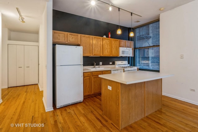 kitchen with sink, white appliances, hanging light fixtures, a center island, and light wood-type flooring