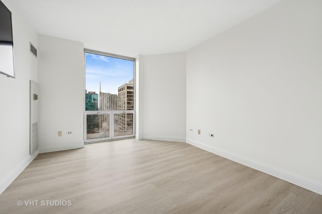 unfurnished room with light hardwood / wood-style flooring and floor to ceiling windows