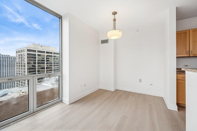 unfurnished dining area featuring a wall of windows and light wood-type flooring