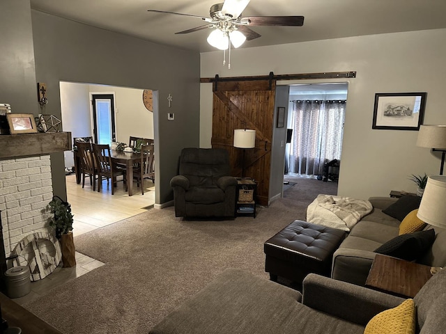 carpeted living room with ceiling fan and a barn door