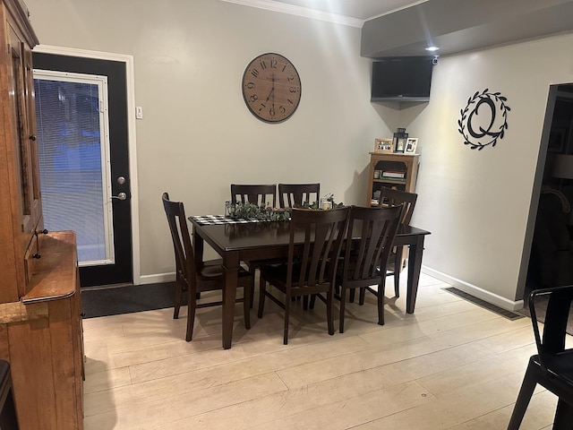 dining area with ornamental molding and light hardwood / wood-style floors