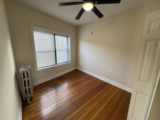 spare room featuring dark hardwood / wood-style flooring and radiator