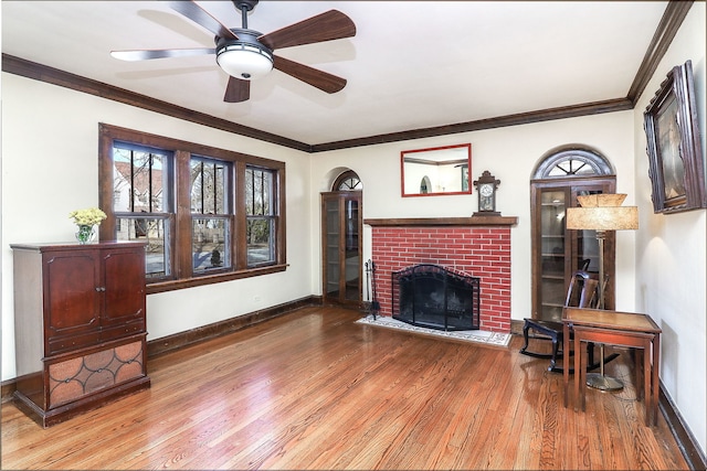 living room with ornamental molding, hardwood / wood-style floors, ceiling fan, and a fireplace