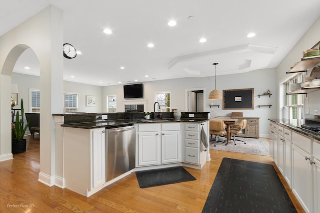 kitchen featuring sink, white cabinetry, decorative light fixtures, stainless steel dishwasher, and light wood-type flooring