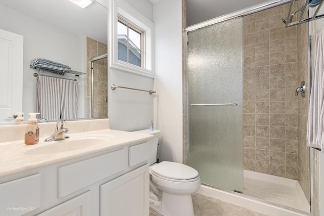 bathroom with tile patterned flooring, toilet, vanity, and walk in shower