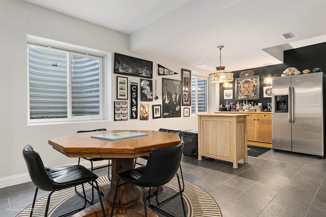 kitchen featuring light brown cabinetry, decorative light fixtures, and stainless steel refrigerator with ice dispenser