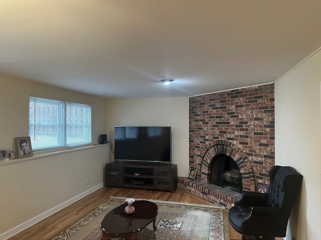 living room with a brick fireplace and wood-type flooring