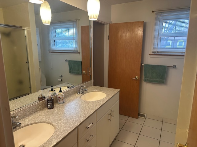 bathroom with a shower with door, vanity, a healthy amount of sunlight, and tile patterned floors