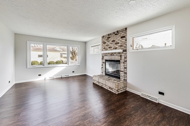 unfurnished living room featuring dark wood-type flooring, a textured ceiling, and a fireplace