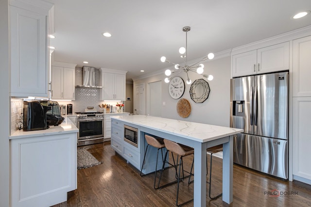 kitchen featuring appliances with stainless steel finishes, decorative light fixtures, white cabinets, dark hardwood / wood-style flooring, and wall chimney exhaust hood