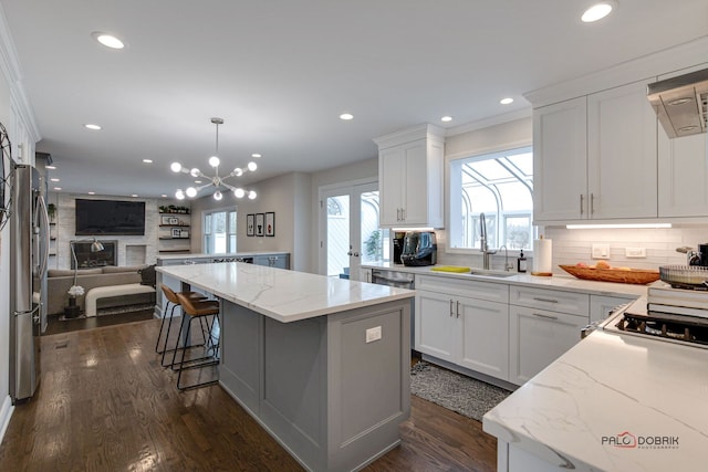 kitchen featuring stainless steel fridge, a center island, white cabinets, and decorative light fixtures