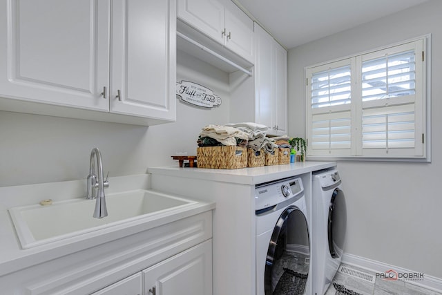 laundry area with sink, washing machine and dryer, and cabinets