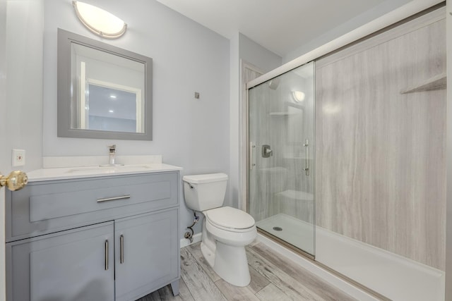 bathroom with vanity, toilet, hardwood / wood-style floors, and walk in shower