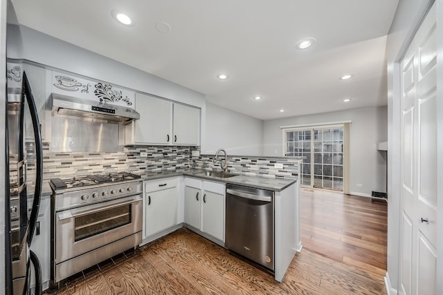 kitchen featuring sink, stainless steel appliances, wood-type flooring, white cabinets, and kitchen peninsula