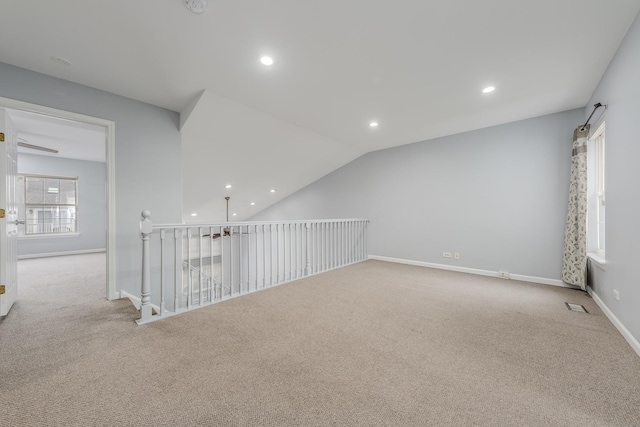 carpeted spare room with vaulted ceiling