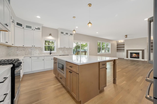 kitchen featuring white cabinetry, decorative light fixtures, appliances with stainless steel finishes, and a kitchen island