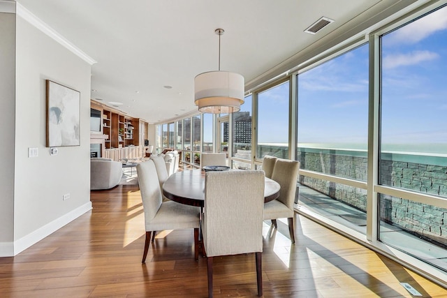 dining area featuring a fireplace, visible vents, wood finished floors, a wall of windows, and baseboards