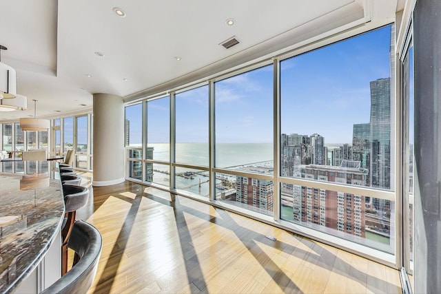 sunroom / solarium with a view of city, a healthy amount of sunlight, visible vents, and a water view