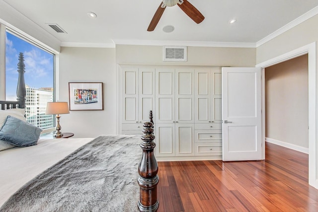 bedroom with dark wood finished floors, visible vents, and crown molding