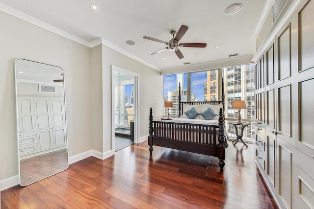 bedroom featuring baseboards, visible vents, ornamental molding, wood finished floors, and a view of city