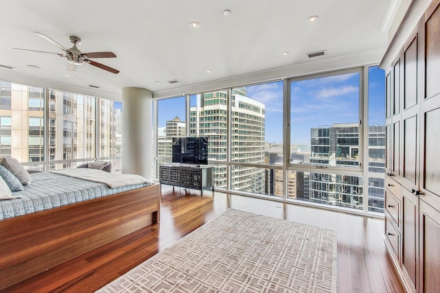 bedroom with a wall of windows, a view of city, visible vents, and wood finished floors