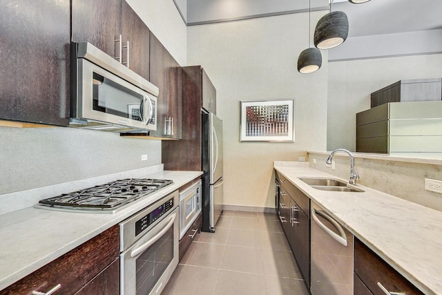 kitchen with dark brown cabinetry, appliances with stainless steel finishes, a sink, and tile patterned floors