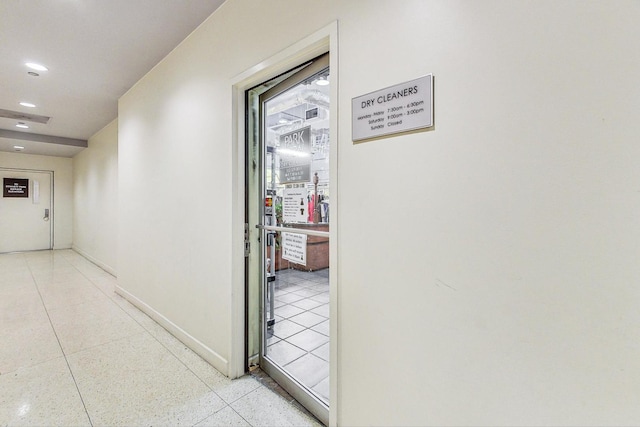 corridor featuring recessed lighting, baseboards, and light tile patterned floors