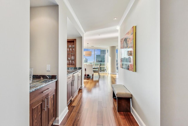 interior space with baseboards, ornamental molding, wood finished floors, a wall of windows, and recessed lighting