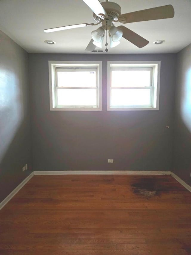 spare room featuring dark wood-type flooring, ceiling fan, and plenty of natural light