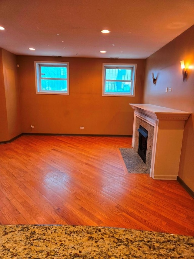 unfurnished living room with a high end fireplace and light hardwood / wood-style floors