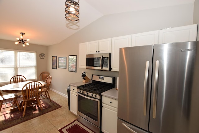 kitchen with light tile patterned floors, stainless steel appliances, white cabinets, vaulted ceiling, and a chandelier