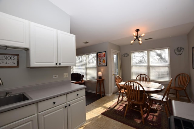 kitchen with white cabinetry, an inviting chandelier, light tile patterned flooring, and sink