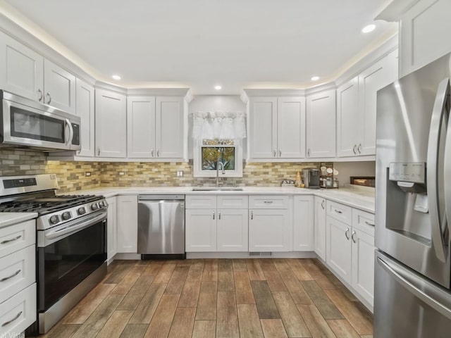 kitchen featuring white cabinetry, appliances with stainless steel finishes, sink, and backsplash