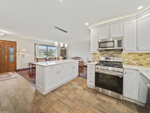 kitchen featuring white cabinetry, decorative light fixtures, decorative backsplash, and appliances with stainless steel finishes