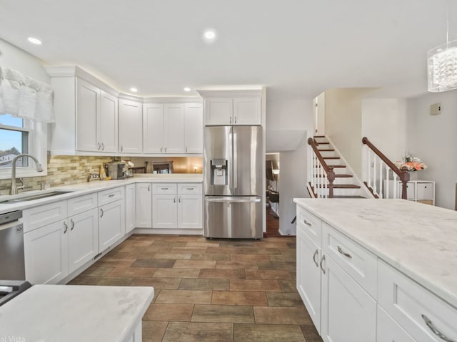 kitchen with tasteful backsplash, sink, white cabinets, and appliances with stainless steel finishes