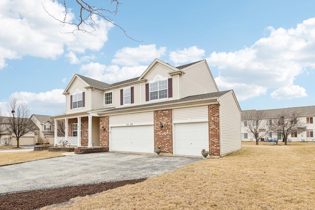 view of property featuring a garage, covered porch, and a front lawn