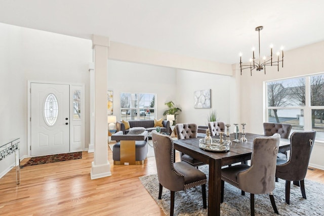 dining room with plenty of natural light, a chandelier, light hardwood / wood-style floors, and ornate columns