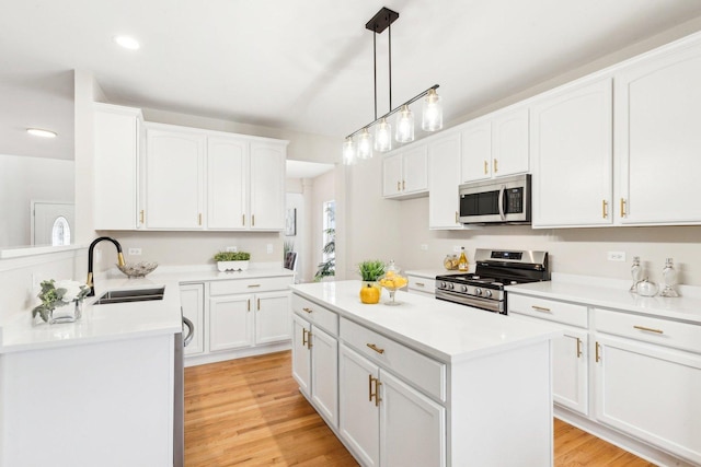 kitchen with stainless steel appliances, sink, pendant lighting, and white cabinets